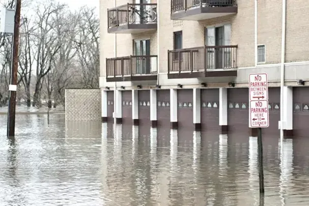 Floodwater covering a street and the ground floor of an apartment building