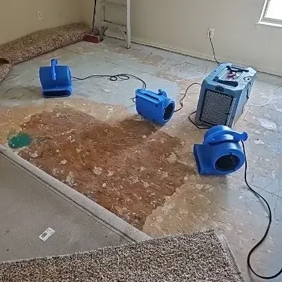 Carpet and pad pulled back so air movers can dry the concrete slab underneath