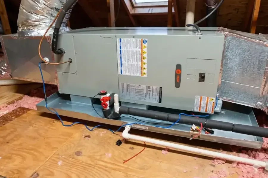 Attic air handler resting in its drain pan with the condensate line attached