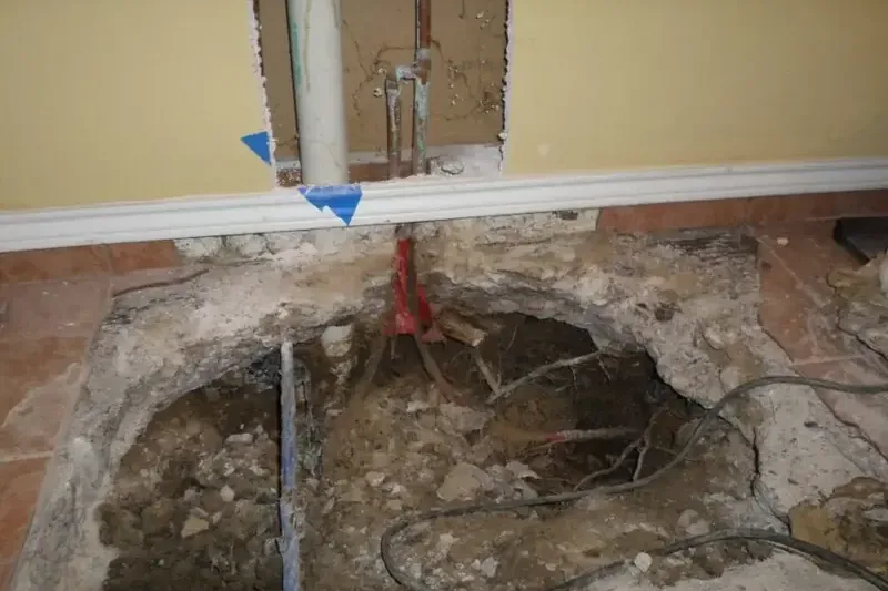 Floor covering pulled back so the leak in the concrete slab underneath can be reached