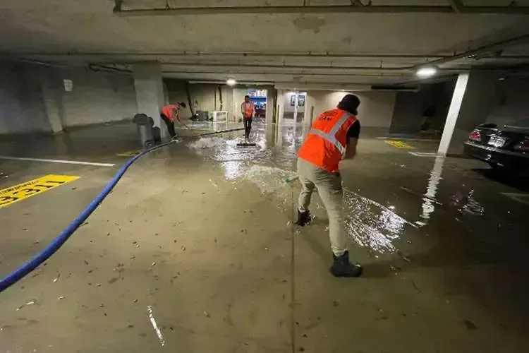 Extraction hose pulling standing water off a flooded concrete floor
